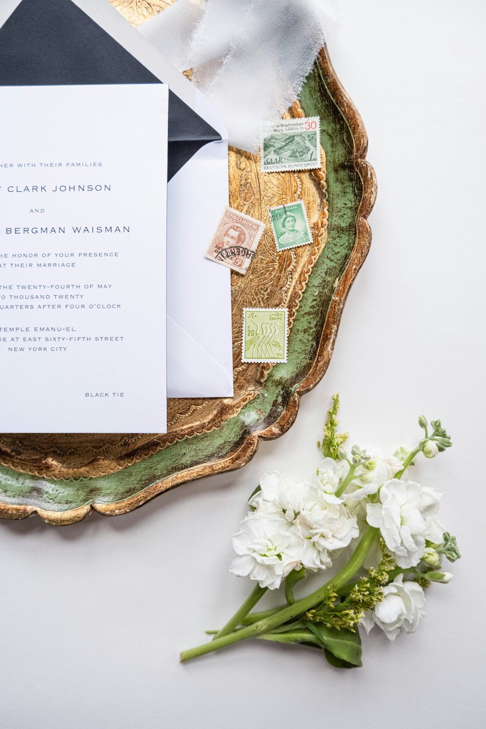 Wedding invitation suite arranged on an ornate gold and green tray.