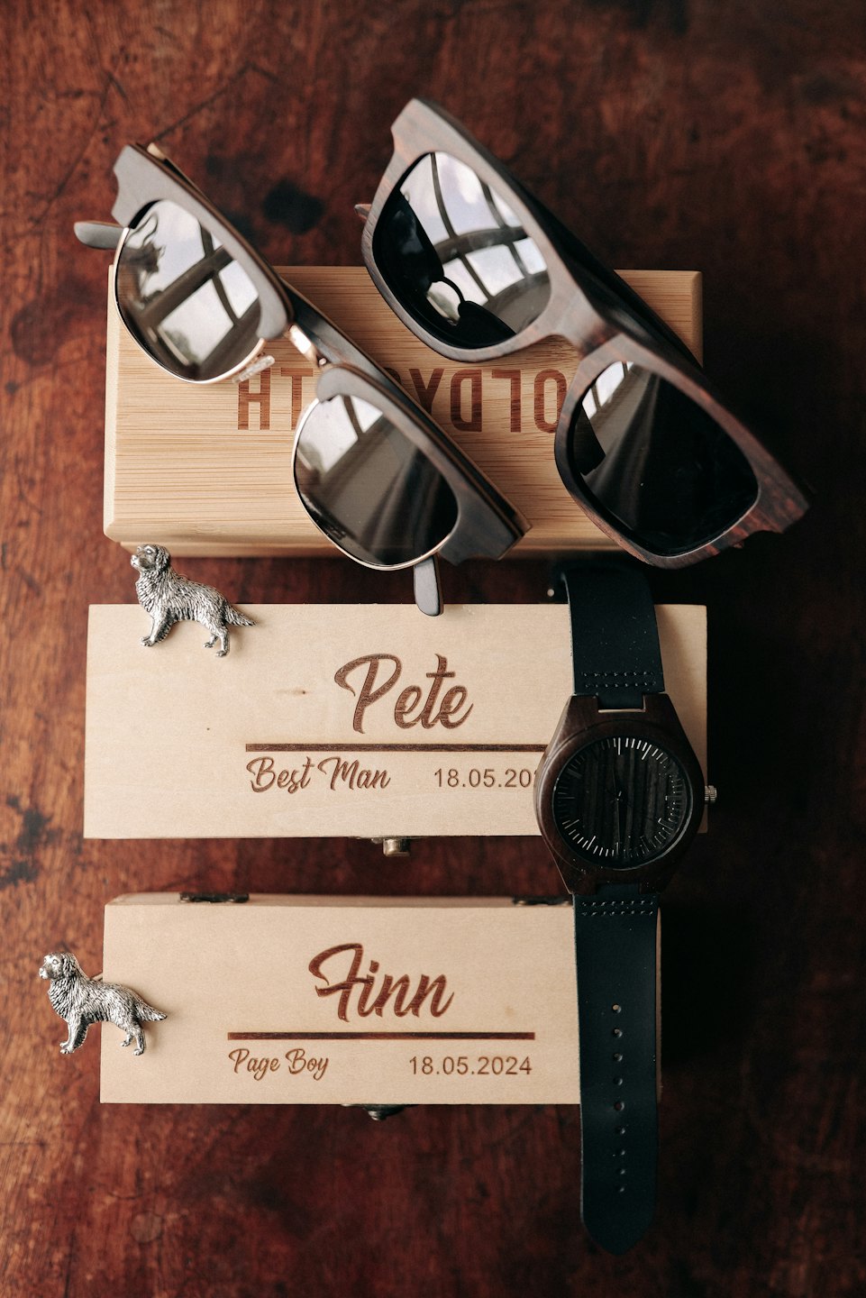 Wedding party gifts arranged on a dark wood table.